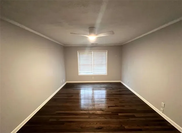 a view of an empty room with wooden floor and window