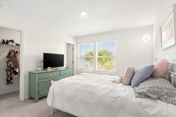 a bedroom with a bed and a flat tv screen on the dresser