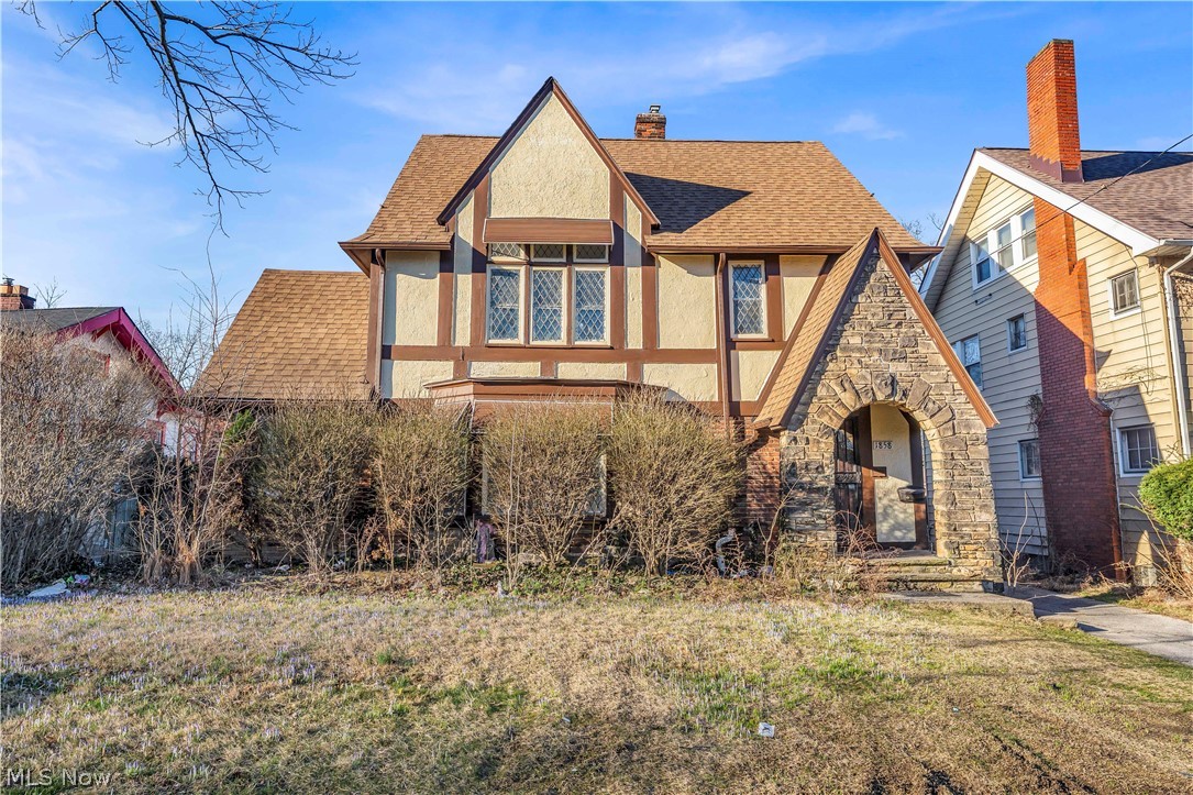 1858 Rudwick Road Cleveland, OH 44112 - Photo 2 of 36 English style home with roof with shingles, stucco siding, a chimney, a front yard, and stone siding