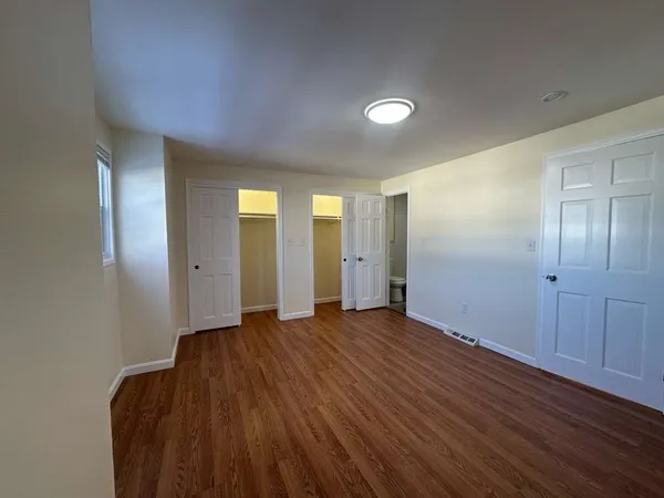 a view of an empty room with wooden floor and closet