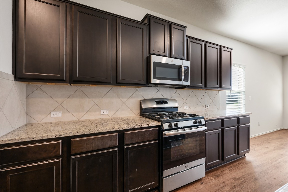160 Copper Lane Kyle, TX 78640 - Photo 11 of 40 a kitchen with granite countertop wooden cabinets and stainless steel appliances