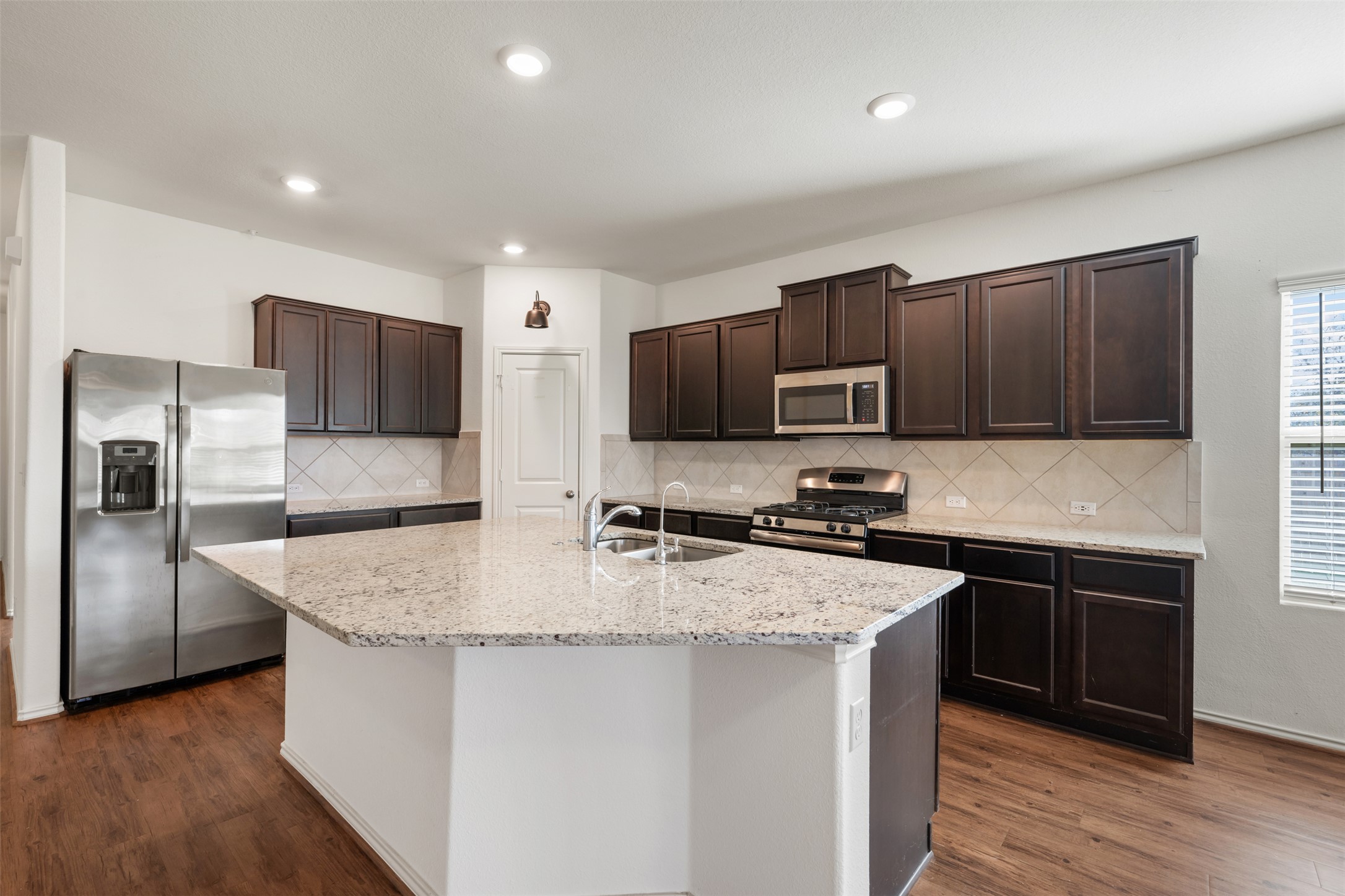 160 Copper Lane Kyle, TX 78640 - Photo 10 of 40 a kitchen with stainless steel appliances granite countertop a sink stove microwave and refrigerator