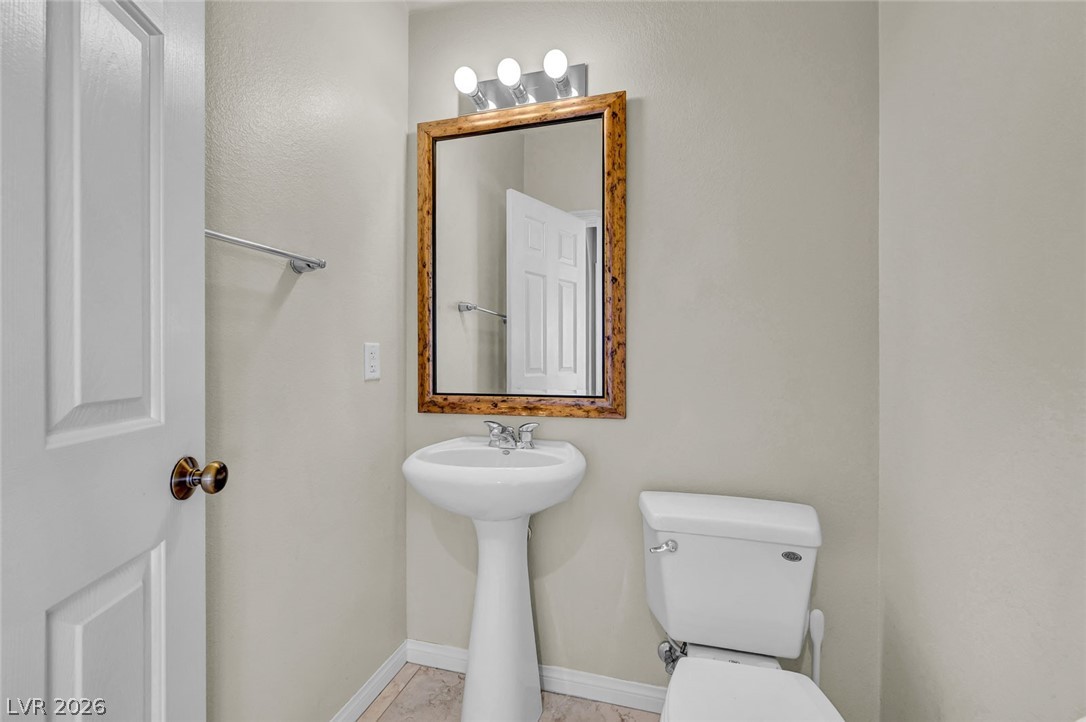 977 Sparkling Light Street Henderson, NV 89052 - Photo 22 of 75 This clean and functional bathroom features a pedestal sink and tile flooring, offering a simple and elegant design.