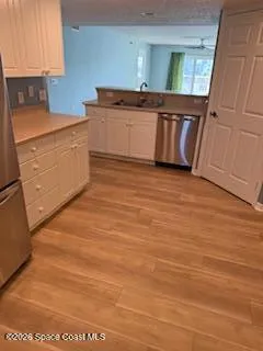 a kitchen with stainless steel appliances wooden floor sink and cabinets