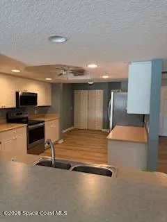 a view of counter top space with stainless steel appliances wooden floor and living room view