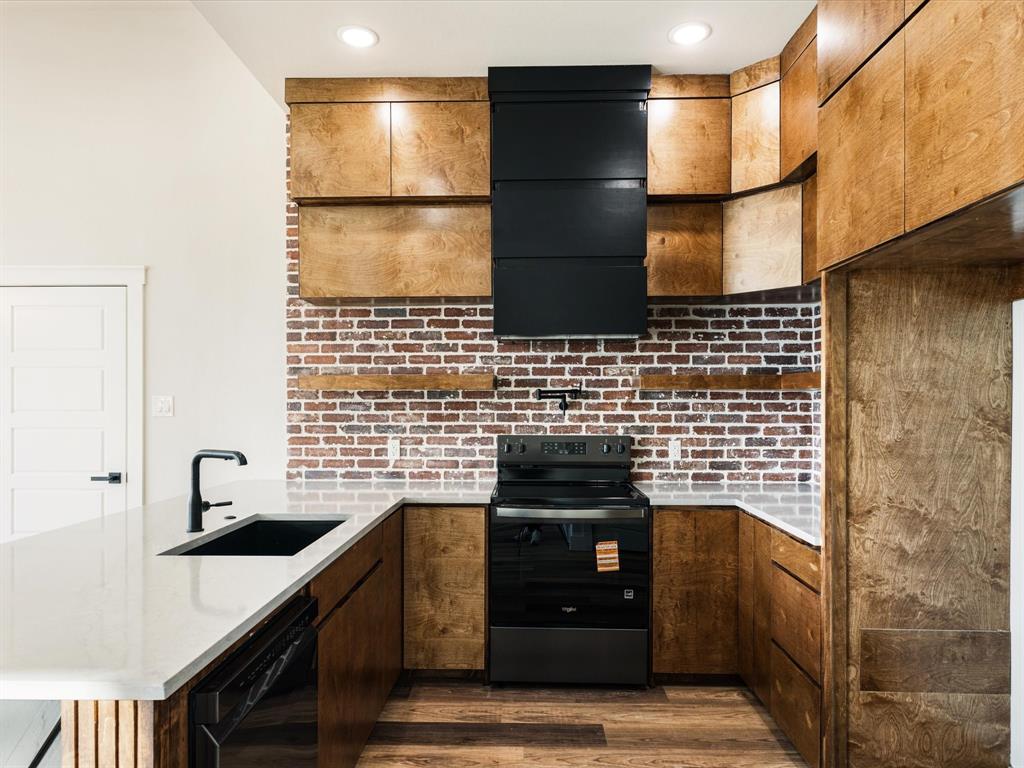 5018 Point La Vista Road Malakoff, TX 75148 - Photo 10 of 32 Kitchen featuring a peninsula, black appliances, dark wood finished floors, light stone counters, and backsplash