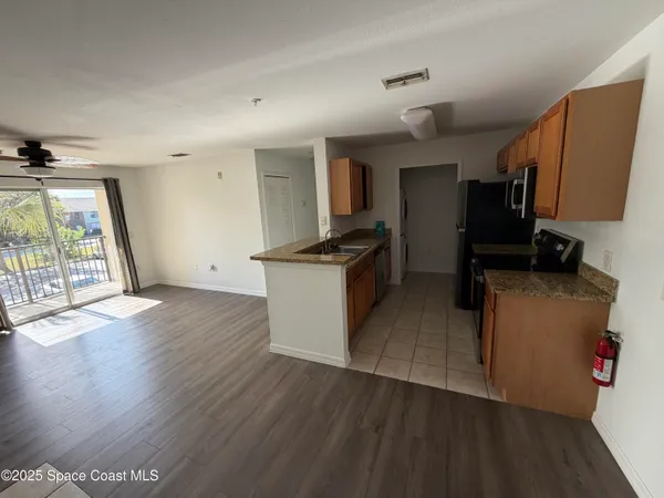 a kitchen with granite countertop a stove top oven a sink dishwasher and a refrigerator with wooden floor