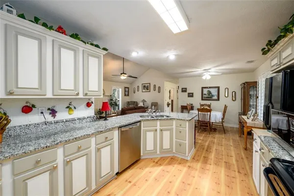 a kitchen with stainless steel appliances granite countertop a sink dishwasher and cabinets with wooden floor