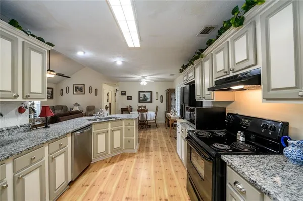 a kitchen with stainless steel appliances granite countertop a stove top oven a sink dishwasher a dining table and chairs with wooden floor