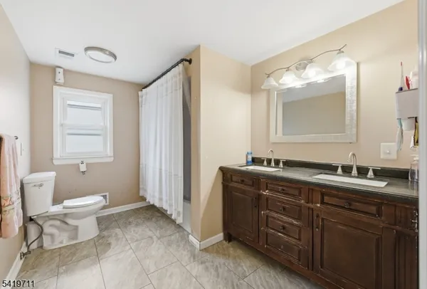 a spacious bathroom with a double vanity sink toilet and a mirror