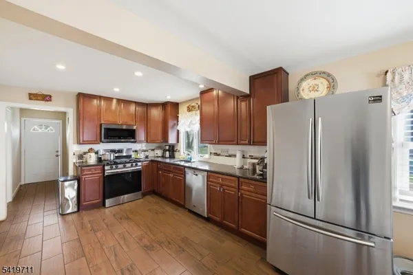 a large kitchen with stainless steel appliances granite countertop a stove refrigerator and a sink