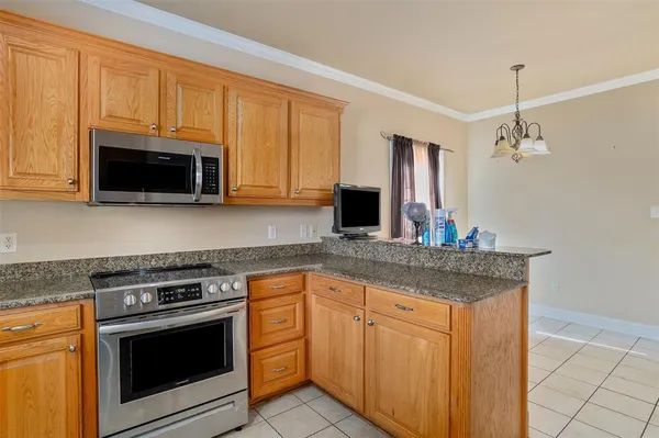 a kitchen with granite countertop a sink dishwasher stove and microwave with wooden cabinets