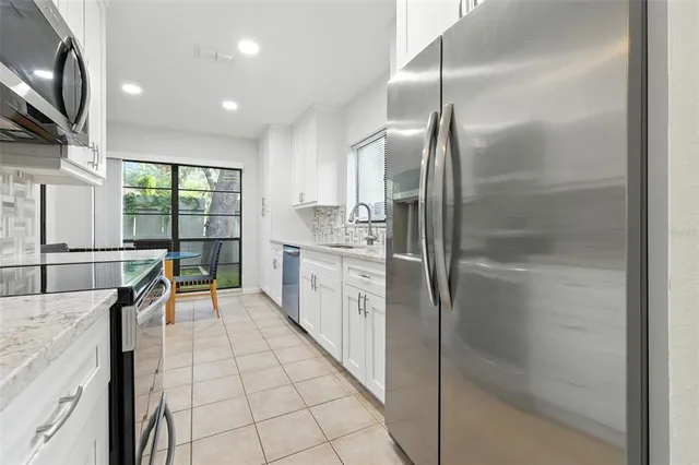 a kitchen with stainless steel appliances granite countertop a sink and a refrigerator