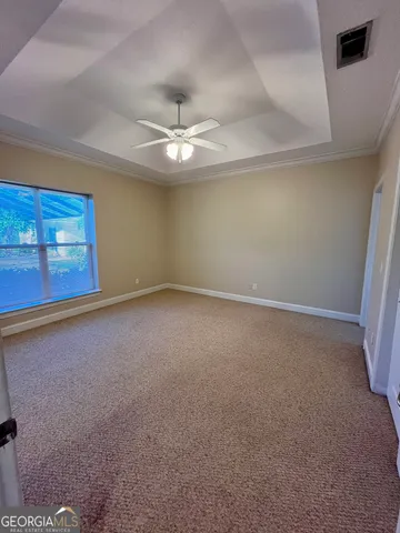 a view of an empty room with a ceiling fan and window