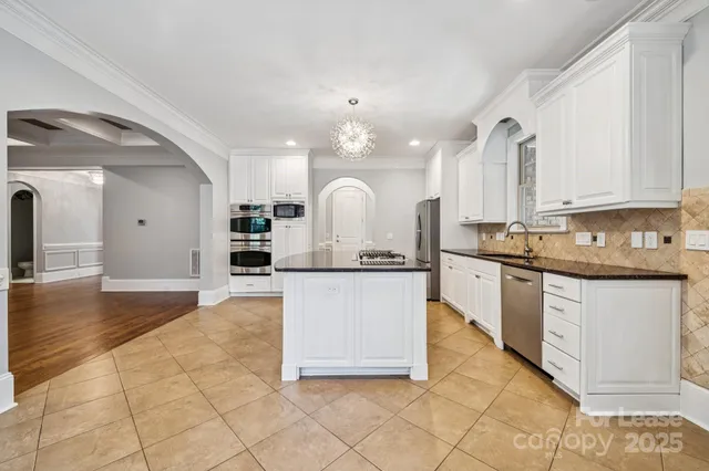 a large kitchen with granite countertop a white stove top oven and cabinets