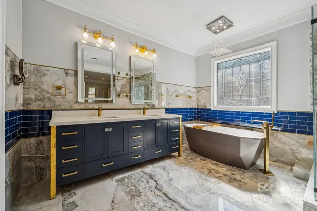 a spacious bathroom with a granite countertop double vanity sink a mirror and a bathtub