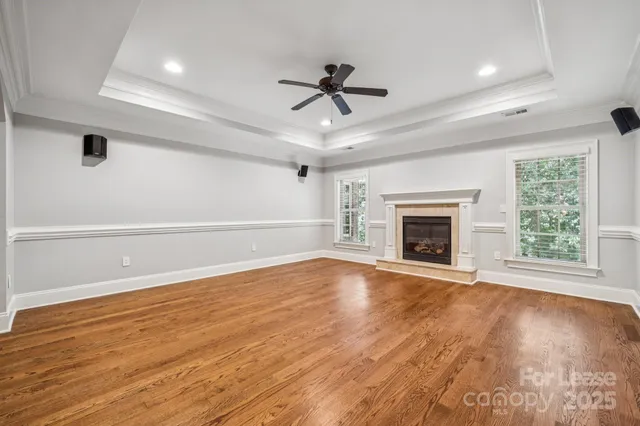a view of an empty room with wooden floor fireplace and a window