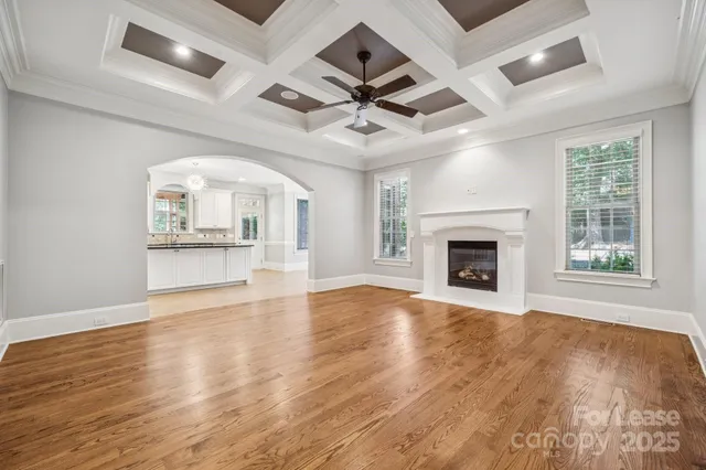an empty room with wooden floor a ceiling fan and windows