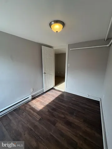 a view of an empty room with wooden floor and window