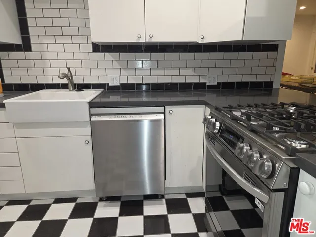 a kitchen with a stove a sink and white cabinets