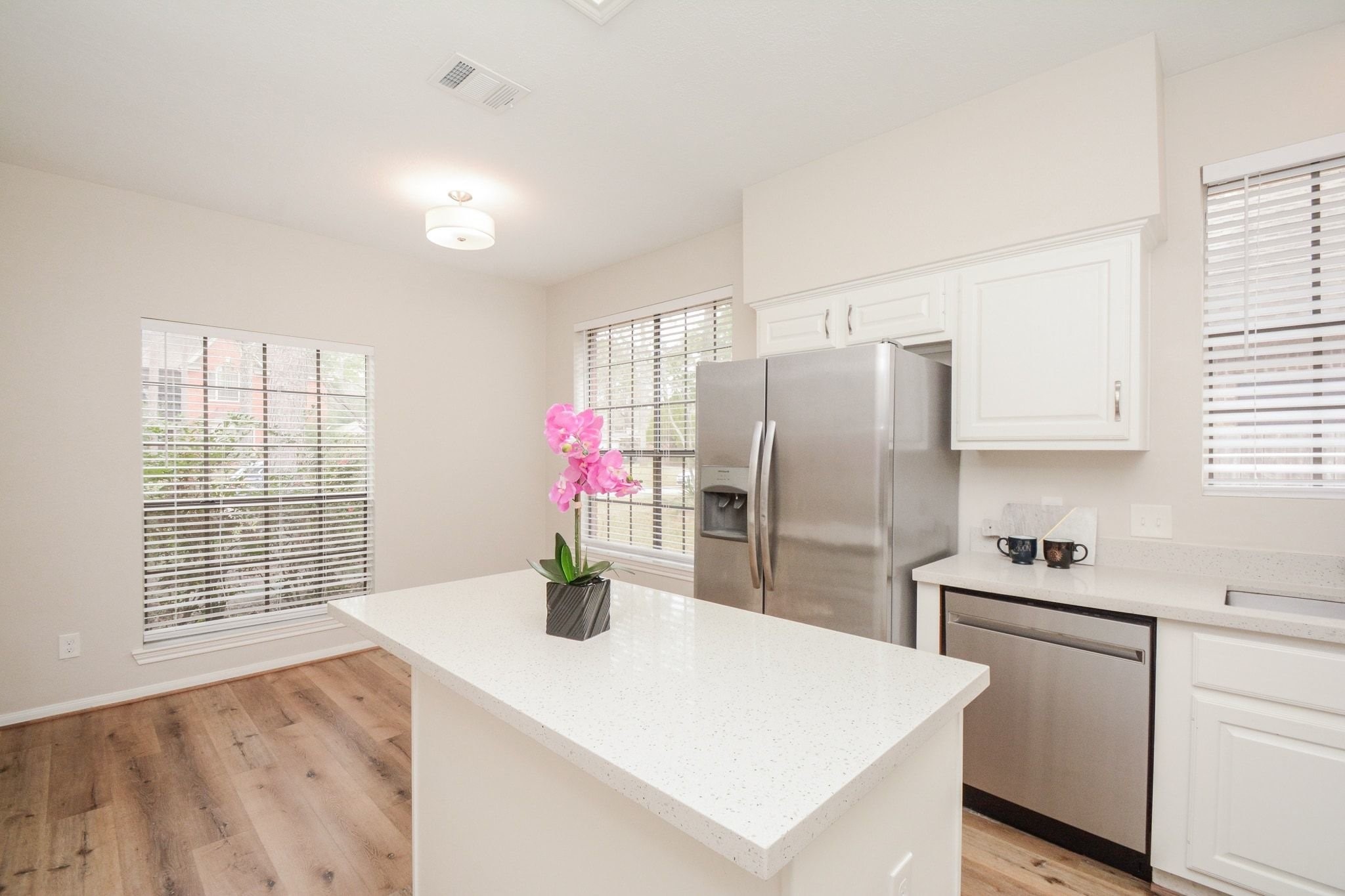 10 Heathstone Place The Woodlands, TX 77381 - Photo 8 of 27 Bright kitchen with modern stainless steel appliances, quartz countertops, and ample natural light from large windows. Features a center island and sleek wood flooring for a contemporary feel.