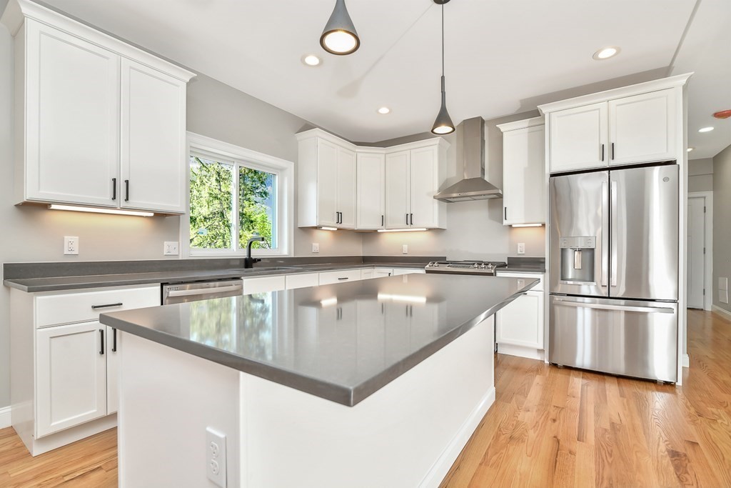 a kitchen with stainless steel appliances granite countertop a refrigerator a sink dishwasher a s kitchen island a stove and a sink with wooden floor