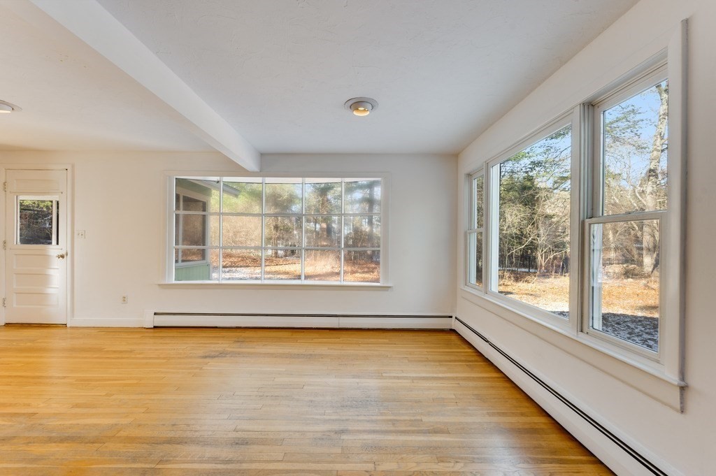 a view of an empty room with a window and wooden floor