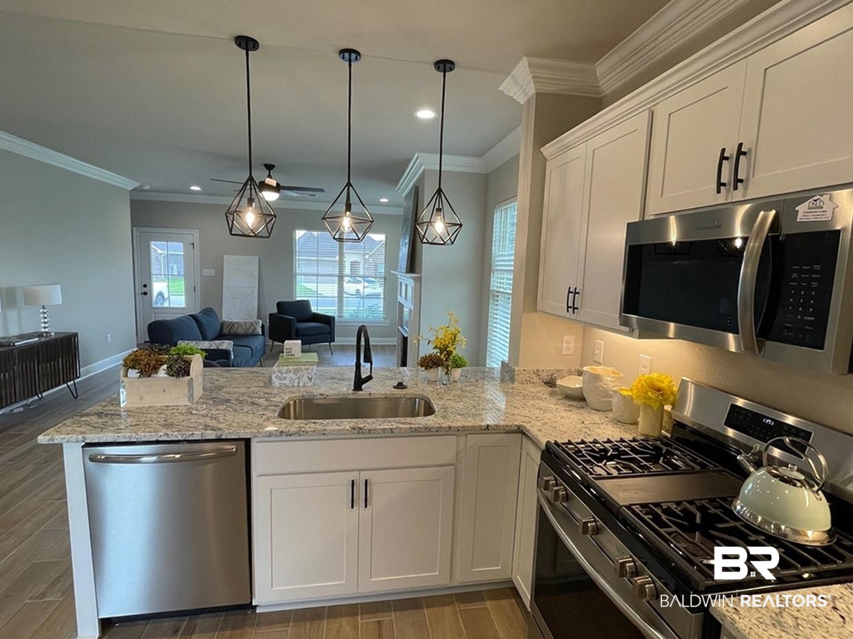 9961 Chipper Lane Foley, AL 36535 - Photo 3 of 16 Kitchen with decorative light fixtures, white cabinets, sink, appliances with stainless steel finishes, and kitchen peninsula
