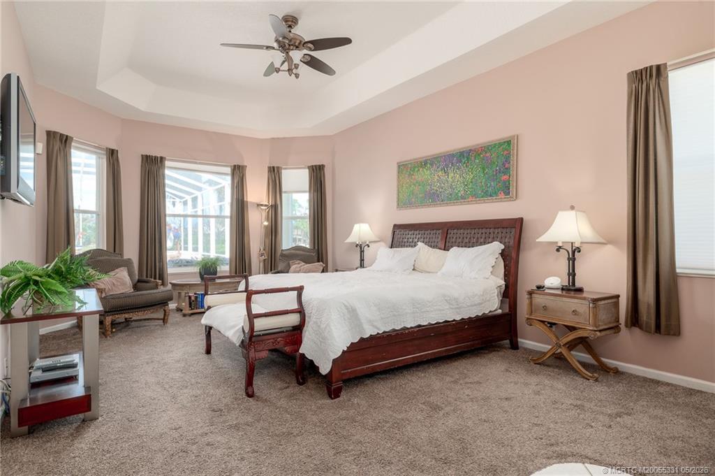 2216 Southeast Stonehaven Road Port St. Lucie, FL 34952 - Photo 18 of 67 a spacious bedroom with a bed a couch and potted plant on the dresser