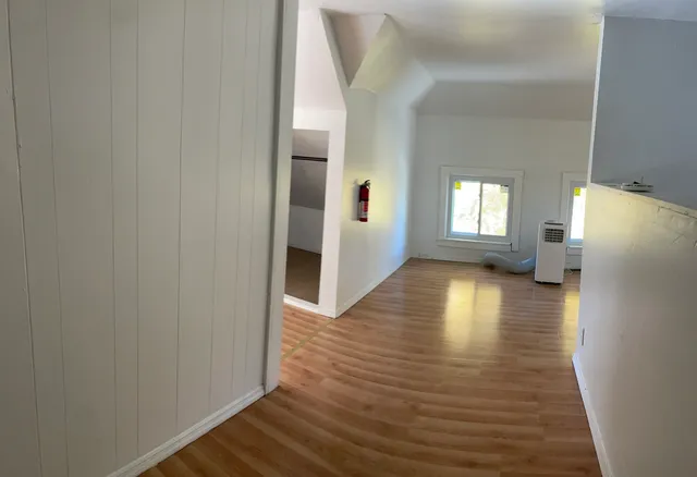 a view of a hallway with wooden floor and a living room