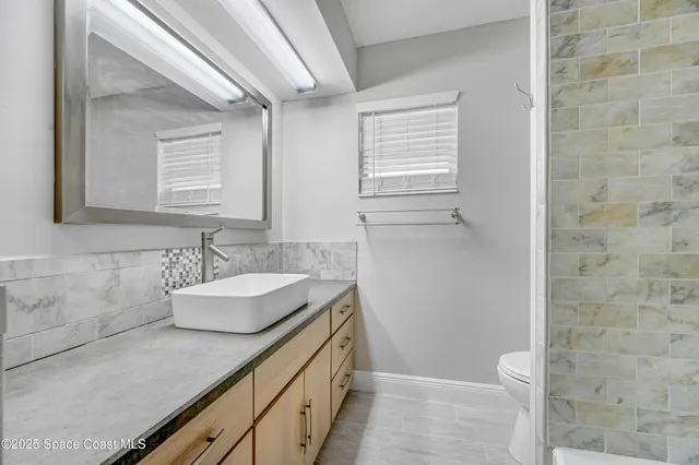 a bathroom with a granite countertop sink a toilet and mirror