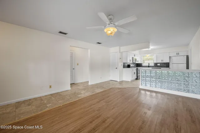 an empty room with wooden floor chandelier and windows