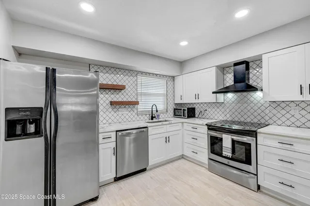 a kitchen with stainless steel appliances granite countertop a refrigerator a stove and a sink