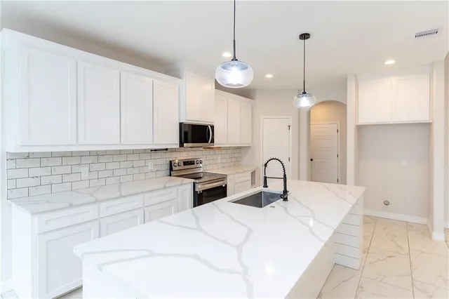 a kitchen with stainless steel appliances kitchen island a white counter space a sink and cabinets