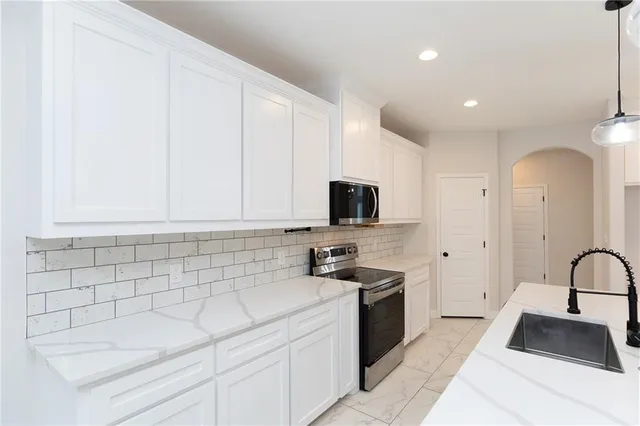 a kitchen with a sink and a stove top oven with white cabinets