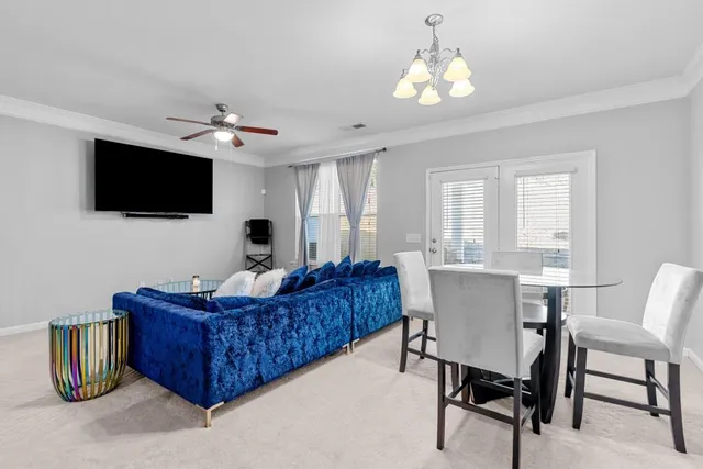 a living room with furniture a flat screen tv and a chandelier