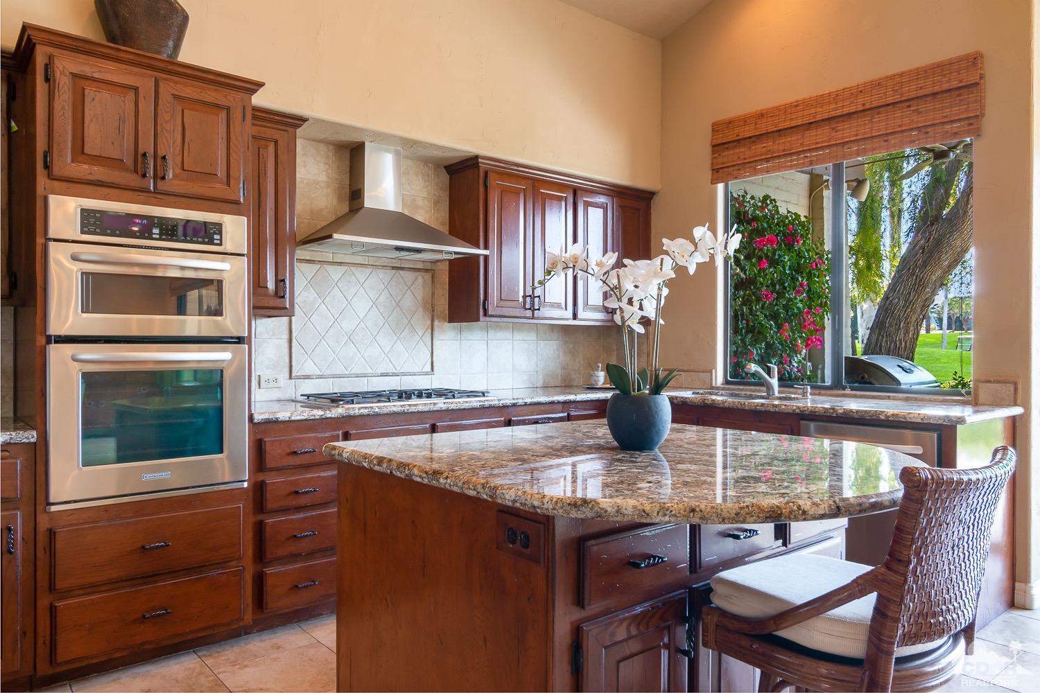 353 Red River Road Palm Desert, CA 92211 - Photo 6 of 28 a kitchen with a stove a refrigerator and a wooden cabinets