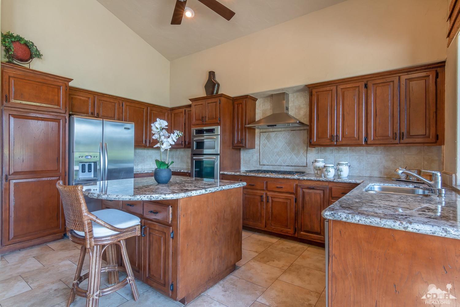 353 Red River Road Palm Desert, CA 92211 - Photo 8 of 28 a kitchen with stainless steel appliances granite countertop a table chairs sink and cabinets