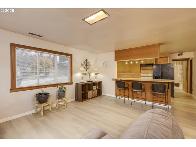 a living room with furniture a dining table and kitchen view with wooden floor