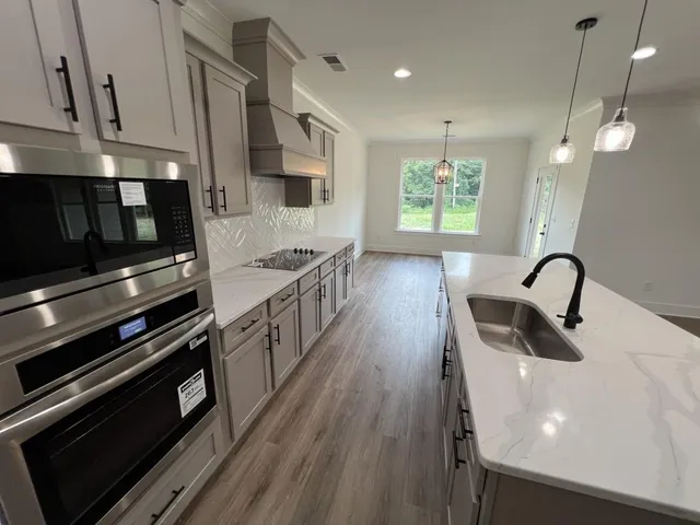 a kitchen with stainless steel appliances a stove a sink a microwave and cabinets