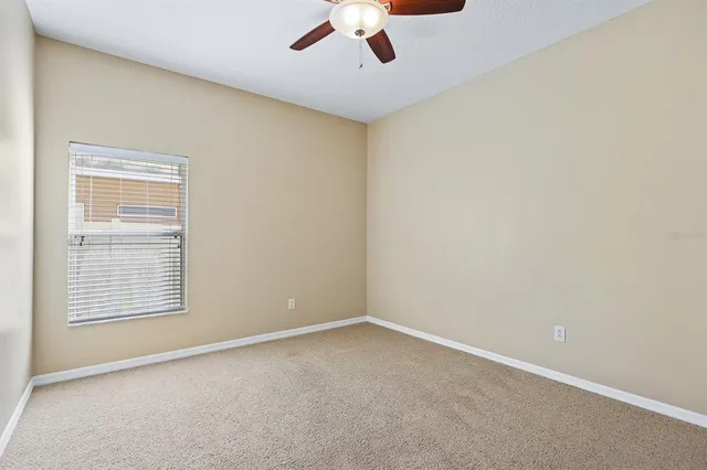 an empty room with a ceiling fan and window