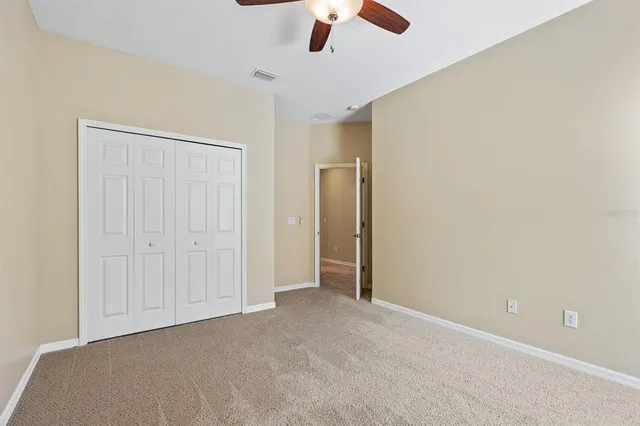 a view of an empty room and chandelier fan