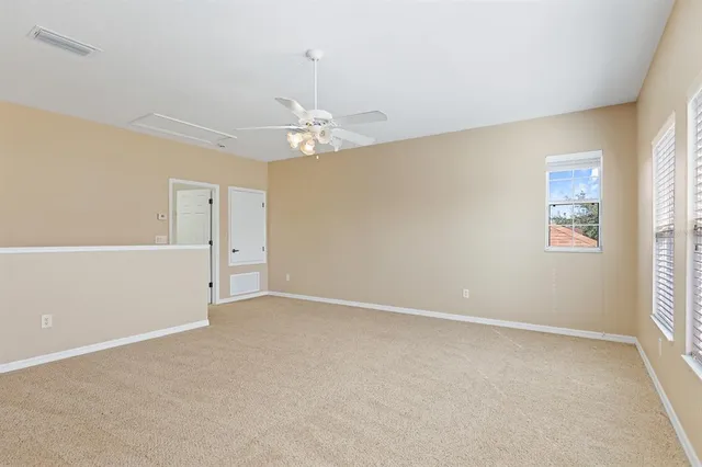 an empty room with windows and chandelier fan