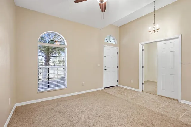 an empty room with windows closet and chandelier fan