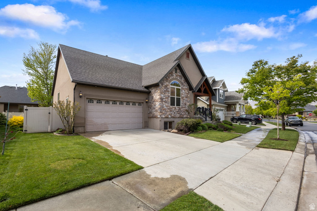 882 Sego Lily Way Mapleton, UT 84664 - Photo 2 of 41 Contemporary home with stone and stucco exterior, featuring a two-car garage, concrete driveway, established landscaping, and a manicured lawn