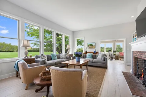 a living room with fireplace furniture and a large window