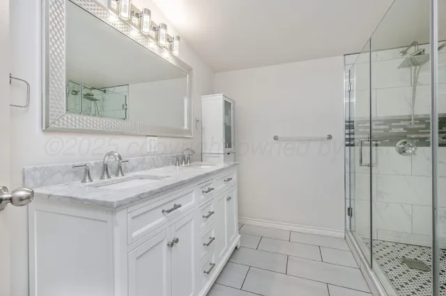 a bathroom with a granite countertop sink a mirror and a shower