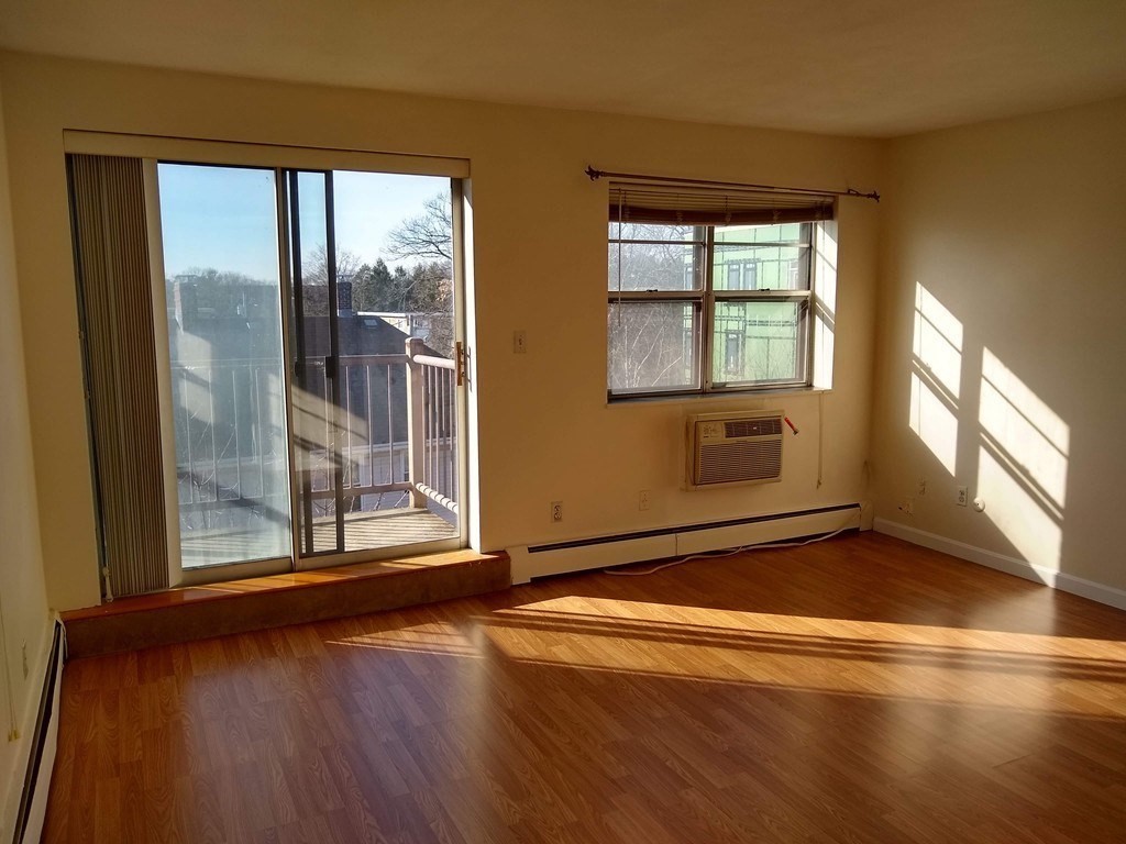 4925 Washington Street, Unit 406 Boston, MA 02132 - Photo 2 of 11 an empty room with wooden floor and windows