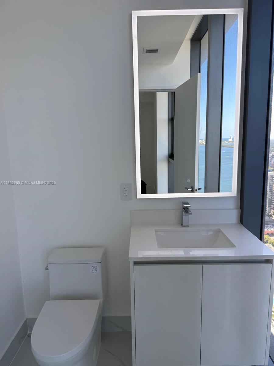 700 Northeast 24th Street, Unit 3701 Miami, FL 33137 - Photo 27 of 53 a bathroom with a toilet sink and mirror