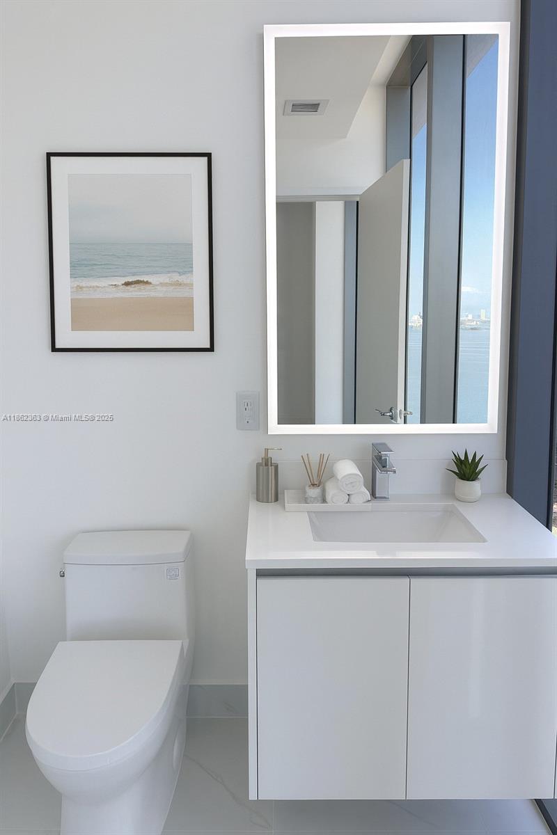 700 Northeast 24th Street, Unit 3701 Miami, FL 33137 - Photo 29 of 53 a bathroom with a toilet a sink and mirror